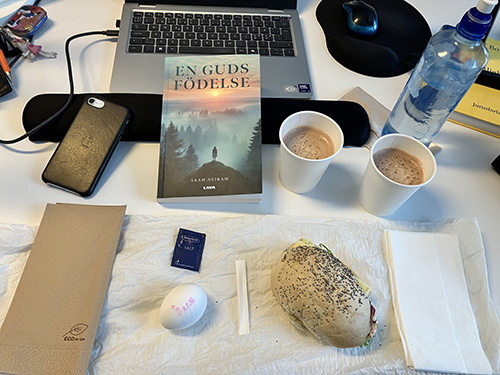 Skrivbordslunch med boken En guds födelse macka och ägg