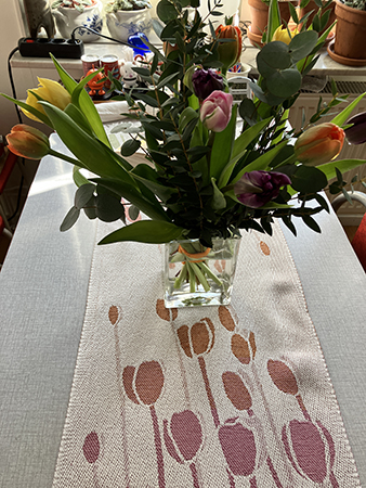 Tulpanbukett med eucalyptus i vas på tulpanduken på köksbordet