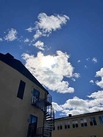 Hus med utomhusspiraltrappa moln på blå himmel