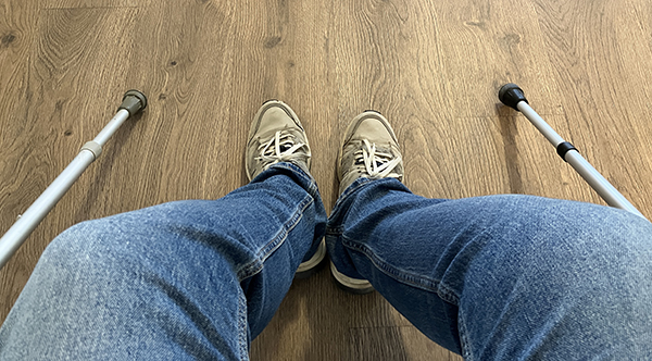 Kryckor jeansben och jympadojor på fötterna i väntrum