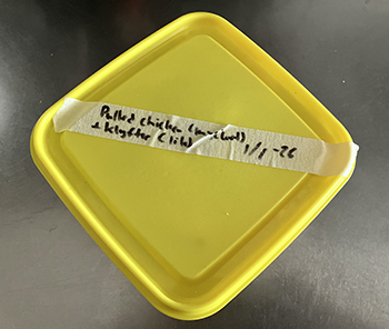 Matlåda med gult lock och pulled chicken o klyftor inuti