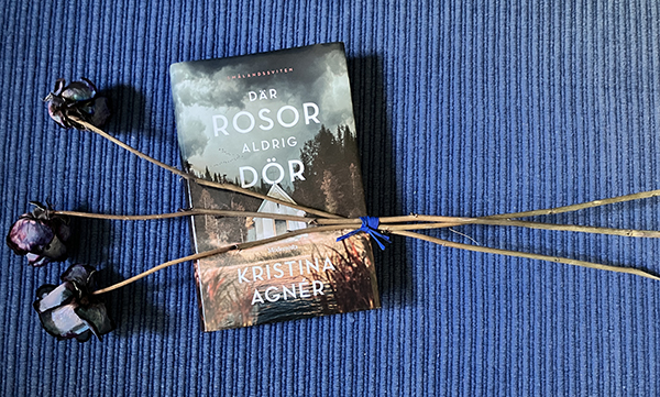 Boken Där rosor aldrig dör med tre torkade blåa rosor ovanpå