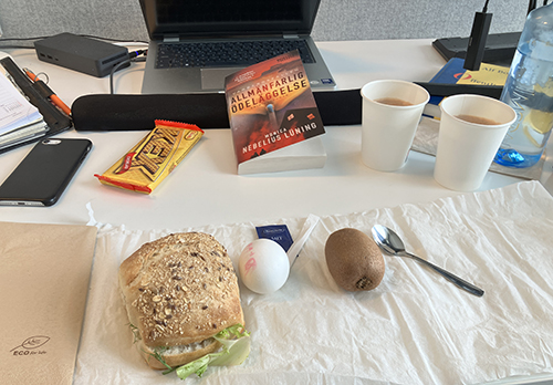 Skrivbordslunch med macka ägg kiwi kexchoklad varm choklad Allmänfarlig ödeläggelse