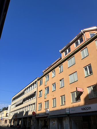Blå junihimmel över rosa hus lite skugga