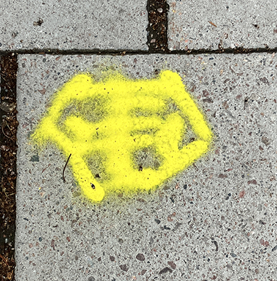 Gult tecken på trottoarplatta
