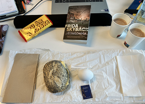 Skrivbordslunch med macka ägg kexchoklad varm choklad o Järnblomma
