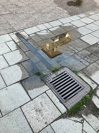 Hus som speglar sig i vattenpöl vid dagbrunn