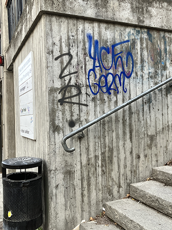 Klotter tags i svart och blått på grå vägg