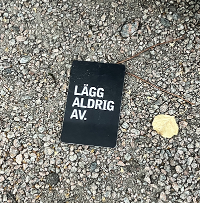 Kort på marken med texten Lägg aldrig av Kort på marken med texten Lägg aldrig av