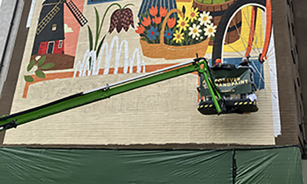 Två som målar muralmålning Vaksala torg i skylift