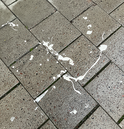Vita färgfläckar på plattor på trottoaren Vita färgfläckar på plattor på trottoaren