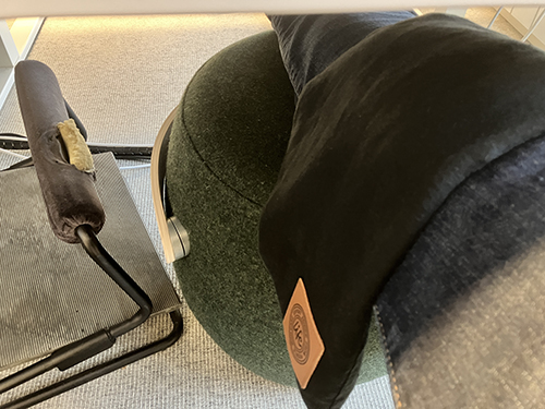 Benet med kyld vetekudde över knäet på fotpall under skrivbordet på jobbet