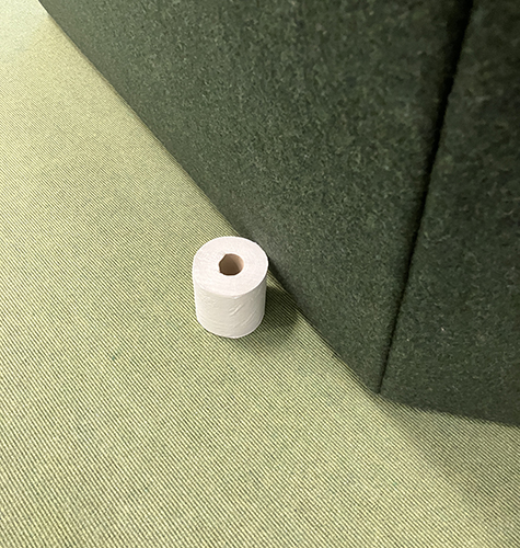 Toapappersrulle på golvet vid en soffa på jobbet